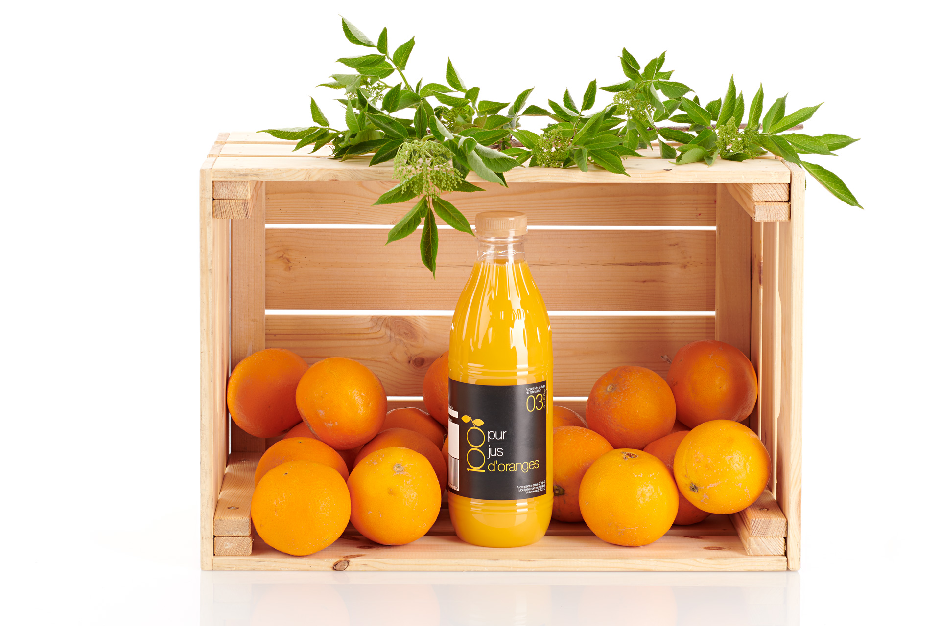 Bouteille de jus et oranges dans une caisse en bois
