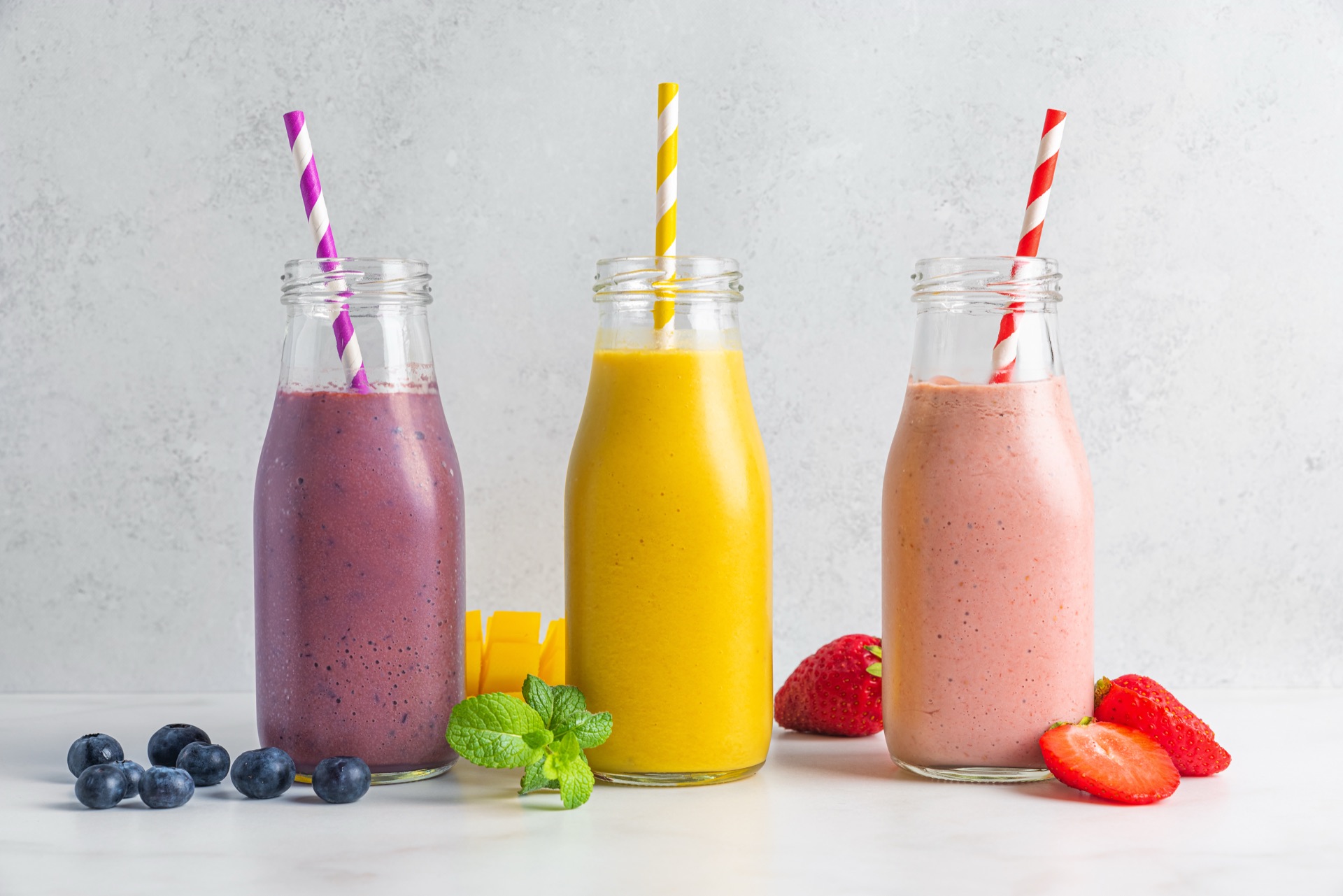Trois bouteilles de smoothies colorés préparées pour le service